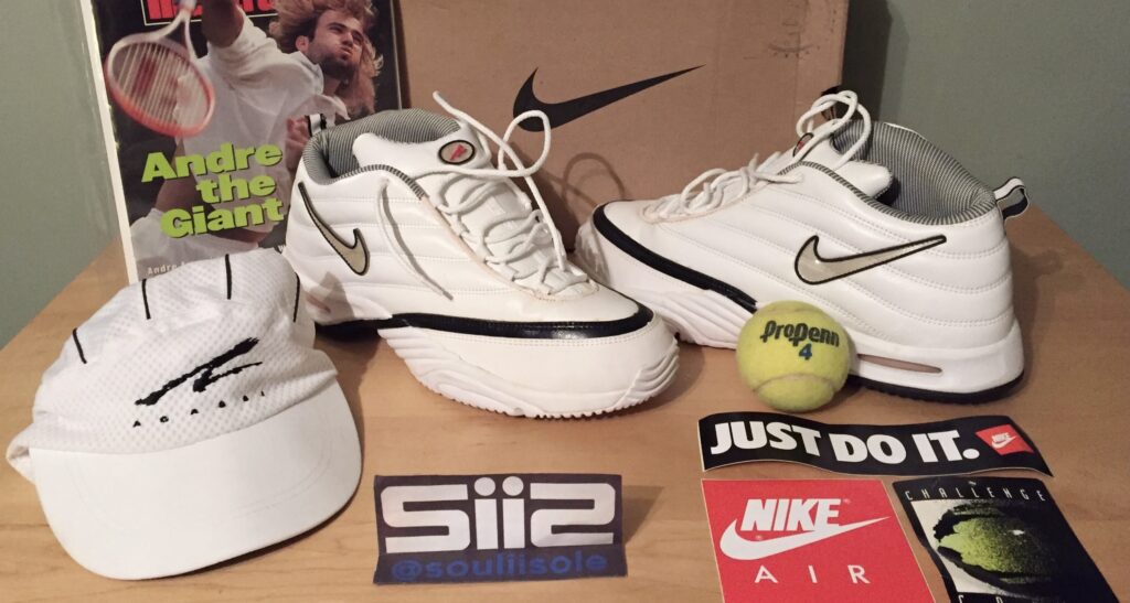 A pair of the Nike Air Assailant in the white/metallic silver/black/comet red colorway along with the OG box, Agassi hat, Sports Illustrated magazine featuring Agassi and tennis balls. 